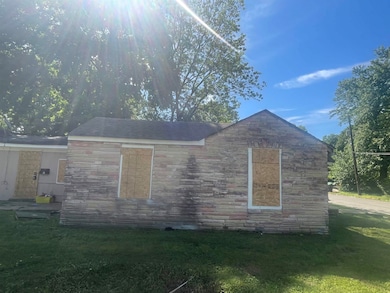 View of side of home with stone siding and a yard