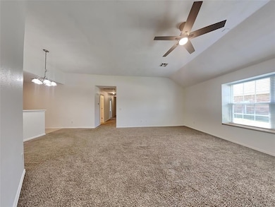 Spare room featuring ceiling fan, carpet floors, lofted ceiling, and baseboards