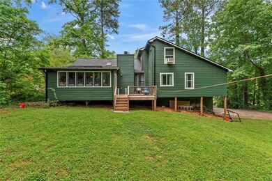 Rear view of house featuring a wooden deck, a yard, and a chimney
