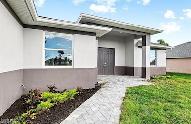 Entrance to property with stucco siding and a yard
