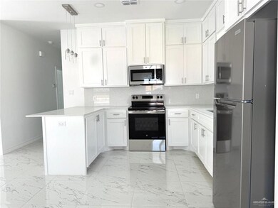 Kitchen featuring backsplash, stainless steel appliances, a peninsula, light marble finish flooring, and white cabinets