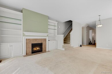 Unfurnished living room with light carpet, a tile fireplace, stairs, and built in shelves
