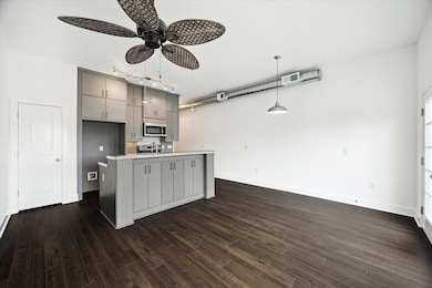 View of the living area towards the kitchen, with ceiling fan and pendent lighting.