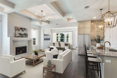 Living area with a chandelier, coffered ceiling, dark wood-style flooring, beam ceiling, and a brick fireplace