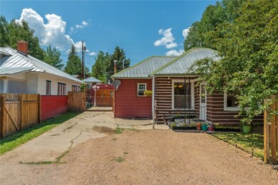 View of side of home with a gate, fence, and metal
