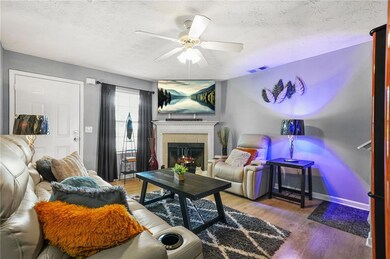 Living area with a textured ceiling, a ceiling fan, wood finished floors, and a fireplace