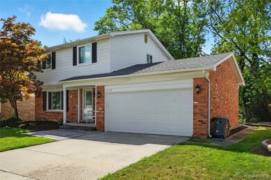 Traditional-style house featuring brick siding, an attached garage, concrete driveway, and a front lawn
