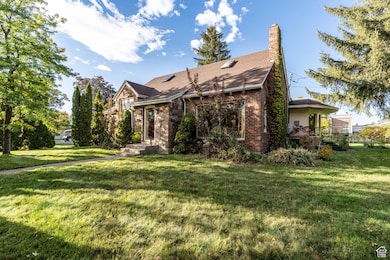 View of front of property with a front yard, a chimney, brick siding, and a shingled roof