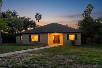 View of front facade with a lawn, roof with shingles, and brick siding