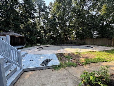 View of swimming pool featuring a fenced backyard, a gazebo, a wooden deck, and view of scattered trees