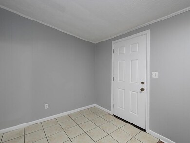 Unfurnished room featuring light tile patterned floors, crown molding, and baseboards