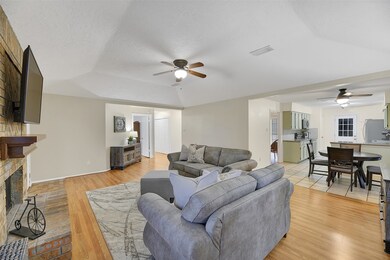 At the heart of the home, this light and bright family room offers an elevated gambrel ceiling with a lighted ceiling fan, continued wood-look laminate floors, and a seamless transition into the adjoining breakfast room and kitchen.