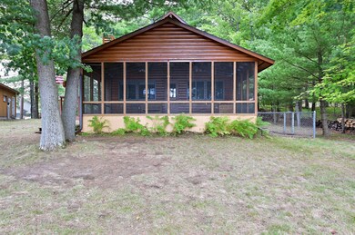 A large lakeside screen porch can be used for dining or relaxing. There is a kennel on the side of the cabin.