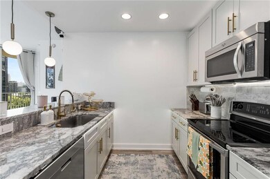 Kitchen featuring stainless steel appliances, wood finished floors, light stone counters, recessed lighting, and pendant lighting