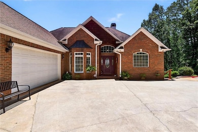View of front of property with a shingled roof, concrete driveway, brick siding, a chimney, and an attached garage