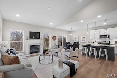 Living area with recessed lighting, lofted ceiling, light wood-type flooring, a chandelier, and a high end fireplace