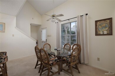 Dining area featuring high vaulted ceiling, light carpet, ceiling fan, and baseboards