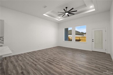 Empty room featuring a tray ceiling, wood finished floors, ceiling fan, and recessed lighting