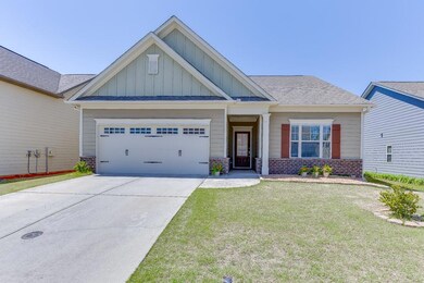 Craftsman inspired home with board and batten siding, an attached garage, a front yard, driveway, and brick siding