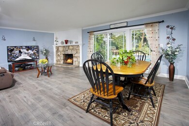 The living room is bathed in natural light and is enhanced by a two-toned designer paint scheme, crown molding, a raised hearth slate stone fireplace, sliding glass doors that lead to the backyard and luxurious wood flooring.