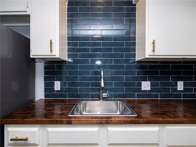 Kitchen with dark countertops, white cabinets, and tasteful backsplash