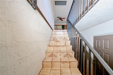 Stairway featuring ceiling fan, a textured wall, a