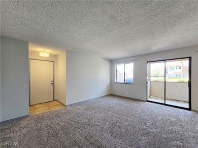 Carpeted spare room with baseboards, a textured ce