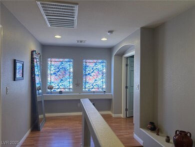 Hall featuring wood finished floors, a textured wall, recessed lighting, and arched walkways