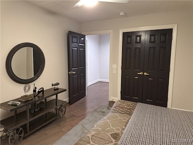 Bedroom with dark wood finished floors, baseboards