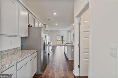 Hallway near the pantry leading to the kitchen. Showcasing the potential storage space for all of your cookware.