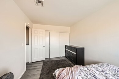 Bedroom with a closet, visible vents, and dark woo