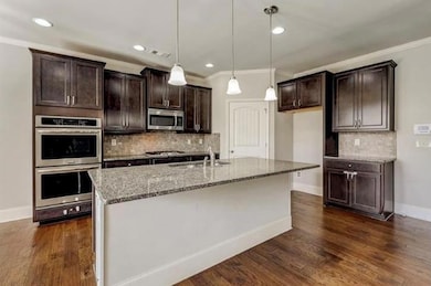 Kitchen with light stone counters, ornamental molding, a sink, tasteful backsplash, and appliances with stainless steel finishes
