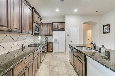 This stunning kitchen displays such a beautiful contrast with the dark stained cabinets, custom neutral paint, granite countertops, light modern backsplash, SS appliances, oversized kitchen island with extra storage, breakfast bar, recessed lighting, and high ceilings!