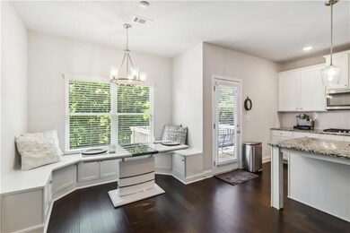 Kitchen with dark wood-style floors, a chandelier, stainless steel microwave, white cabinets, and recessed lighting