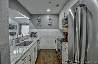 The galley kitchen features upgraded white cabinet