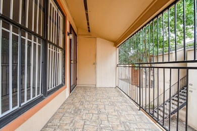 This photo shows a covered balcony with stone tile