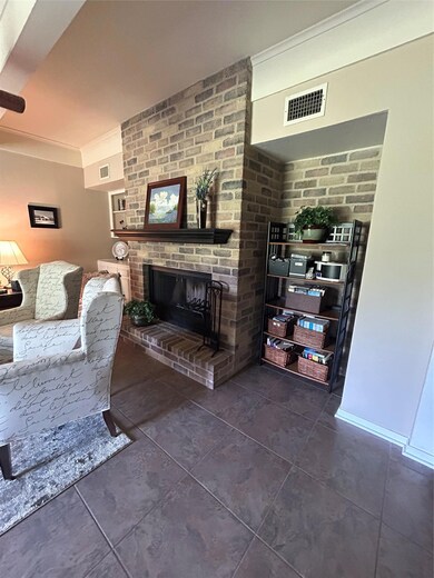 Living room featuring a brick fireplace, dark tile patterned floors, and crown molding