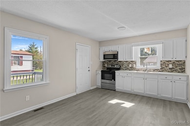 Kitchen with white cabinets, backsplash, light har