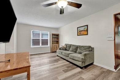 Living room with baseboards, a textured ceiling, l