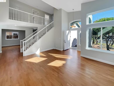 Entrance foyer featuring a high ceiling, a chandelier, light wood finished floors, and stairs
