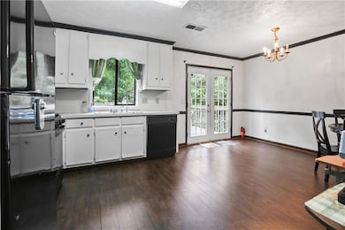 Kitchen featuring dishwasher, freestanding refrigerator, light countertops, ornamental molding, and a textured ceiling