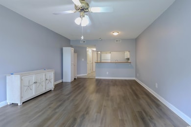 Unfurnished living room featuring wood finished floors, a ceiling fan, and baseboards
