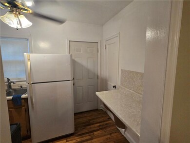 Kitchen with freestanding refrigerator, a sink, ceiling fan, dark wood finished floors, and light countertops
