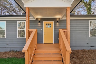 View of exterior entry with crawl space and a deck