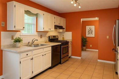 Kitchen with stainless steel appliances, backsplash, light countertops, and white cabinets