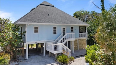Back of house with stairs, a carport, and roof with shingles