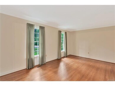 Spacious living room has wood floors, two bright w