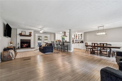 Living room with light wood finished floors, a fireplace, and a textured ceiling