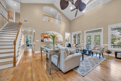 Living area featuring ceiling fan, stairway, high vaulted ceiling, light wood finished floors, and french doors