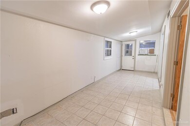 Empty room featuring light tile patterned floors and vaulted ceiling